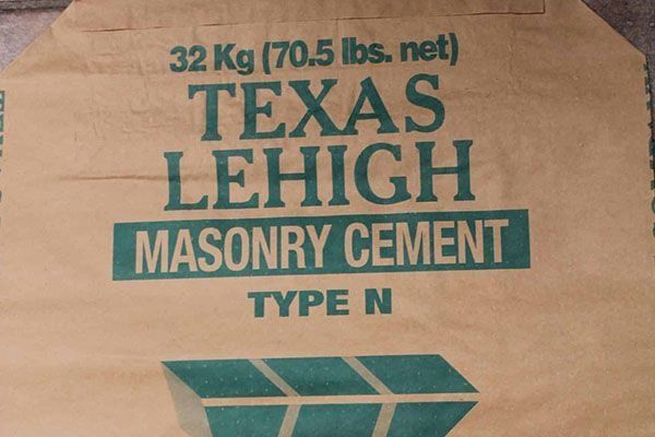 Close-up of a Texas Lehigh masonry cement bag. It is tan with green text indicating