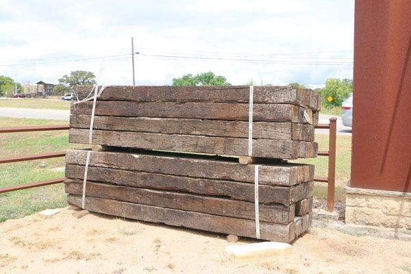 Stacked, weathered wooden railroad ties bound with white straps outside.