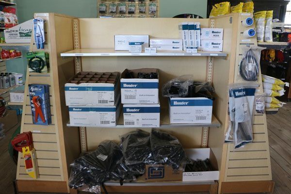 Shelves stocked with irrigation system supplies in a store; boxes, tubing, and tools are displayed.