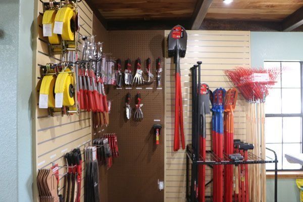 Gardening tools displayed on a store wall: shovels, rakes, trowels, and measuring tapes.