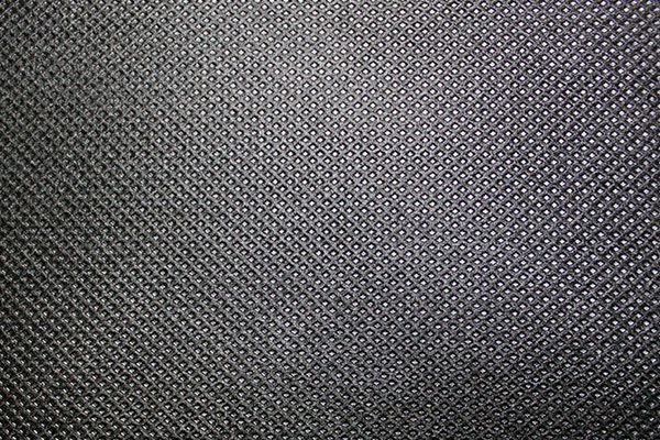 Close-up of a dark gray fabric with a repeating textured pattern of small, raised dots.