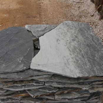 Stack of gray and black flagstones, varying in size and shape.