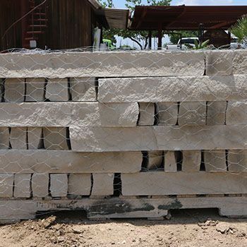 Stone blocks stacked in a wire mesh, forming a wall on a construction site.
