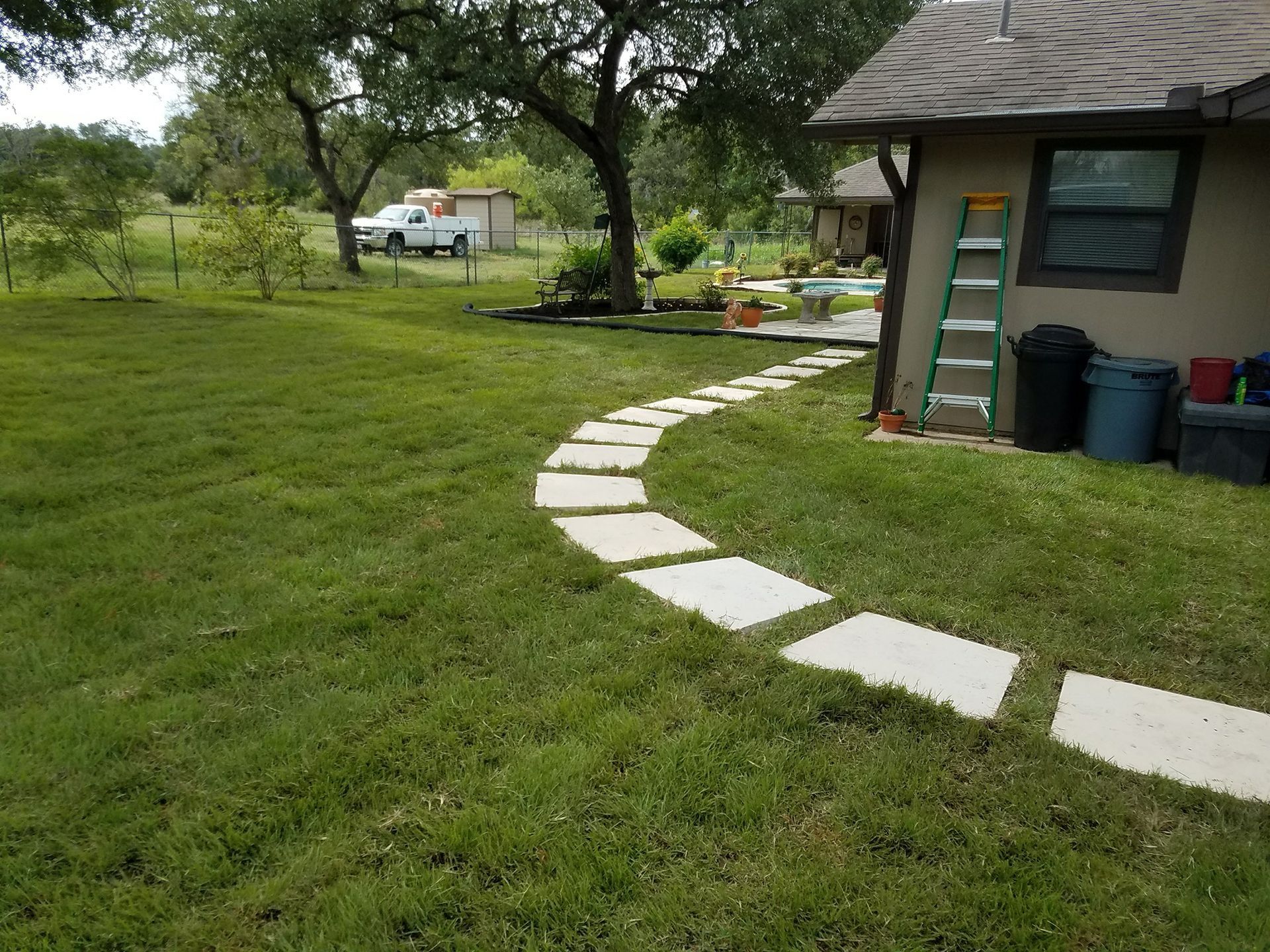 Stone path winds through a grassy yard towards a house.