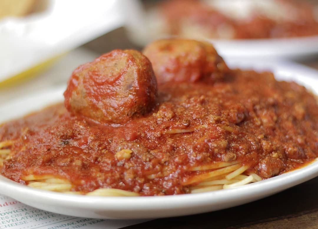 A plate of spaghetti and meatballs with sauce on a table.