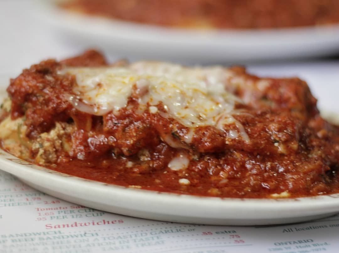 A close up of a plate of food with sauce and cheese on a table.