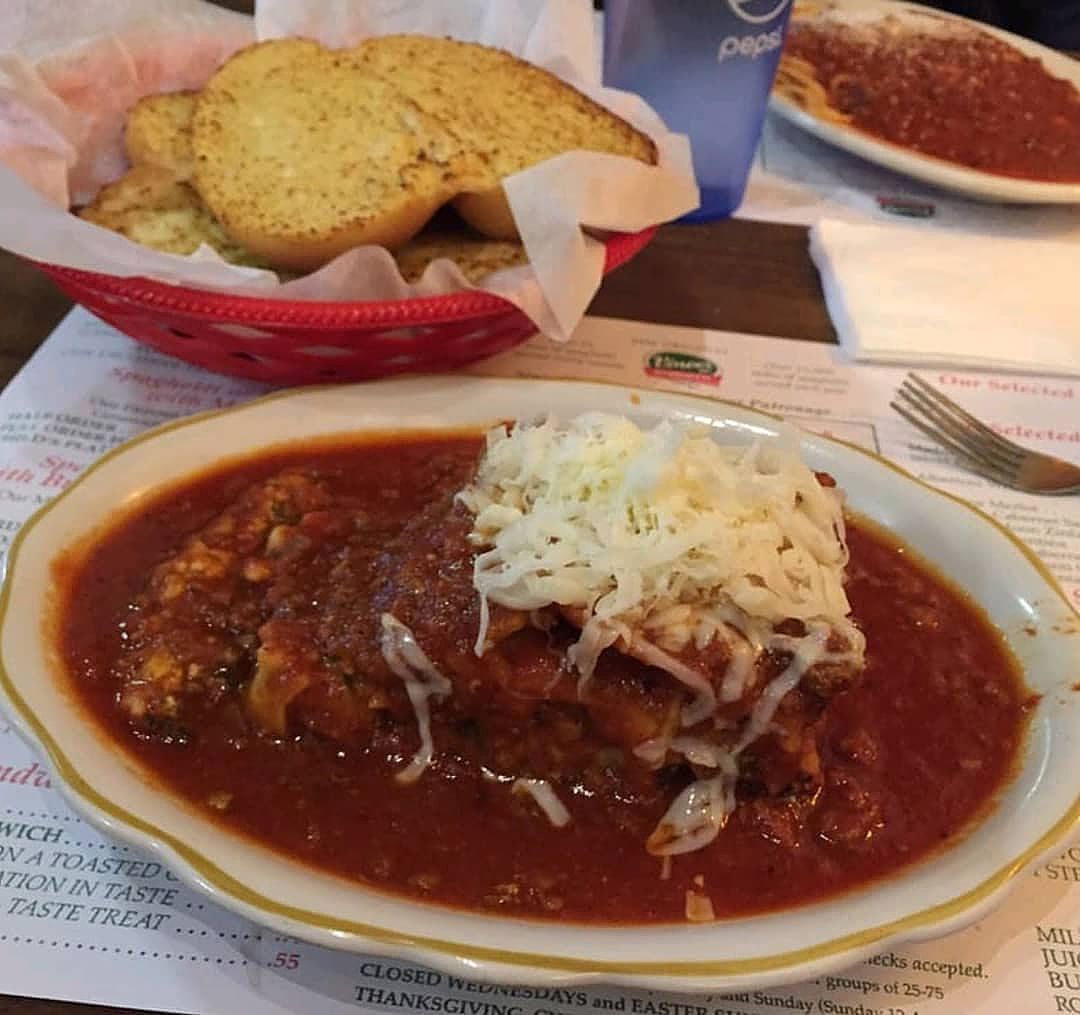 A plate of food on a table next to a basket of garlic bread