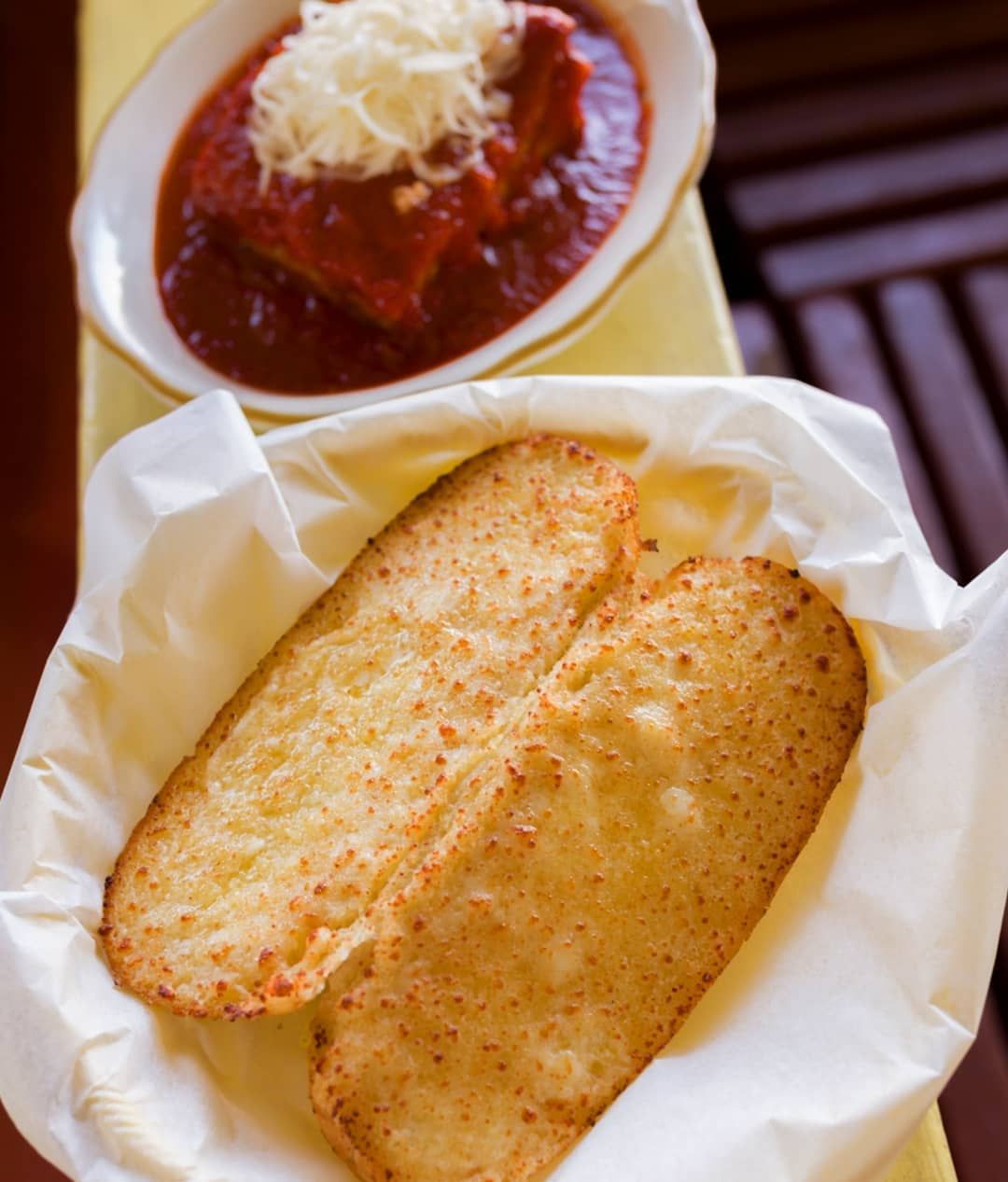 A bowl of garlic bread next to a bowl of sauce