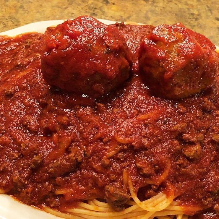 A plate of spaghetti with meatballs and sauce on top
