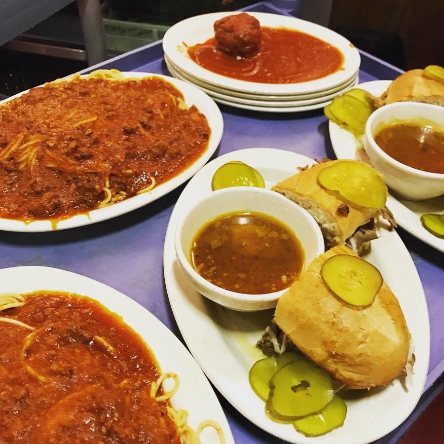 A tray of food including spaghetti meatballs and pickles