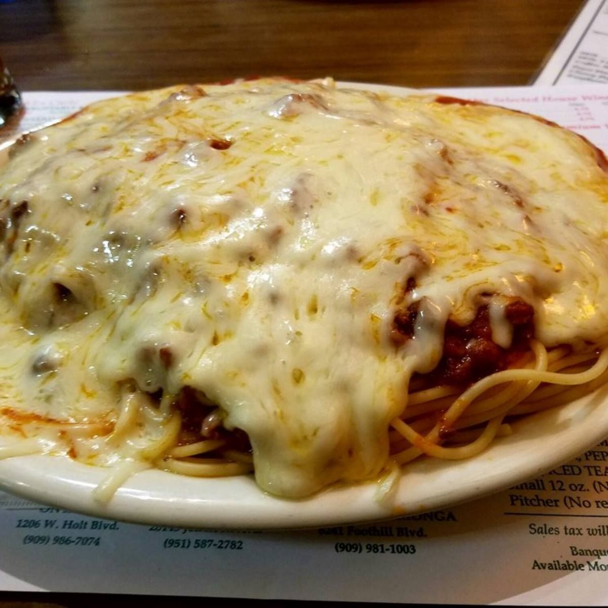 A plate of spaghetti with sauce and cheese on a table