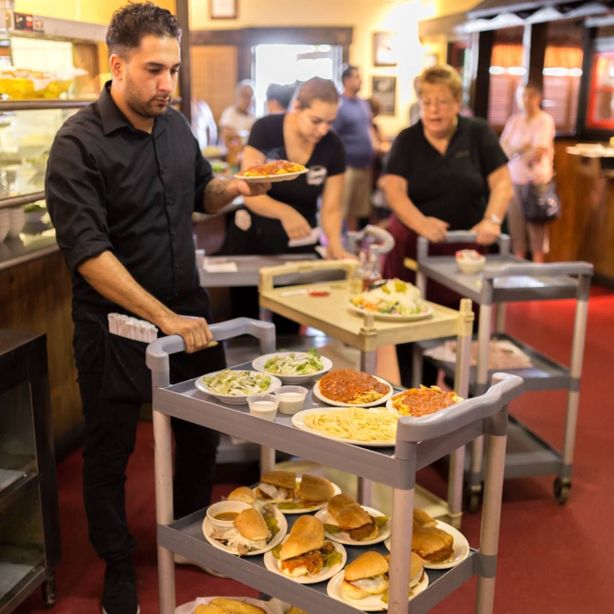 A man is pushing a cart full of food in a restaurant