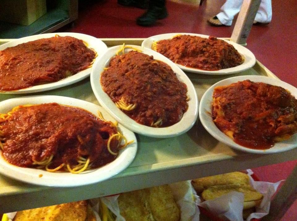 Four plates of spaghetti with sauce on a tray