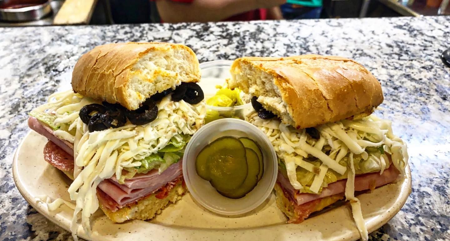 A sub sandwich is sitting on a white plate on a counter.