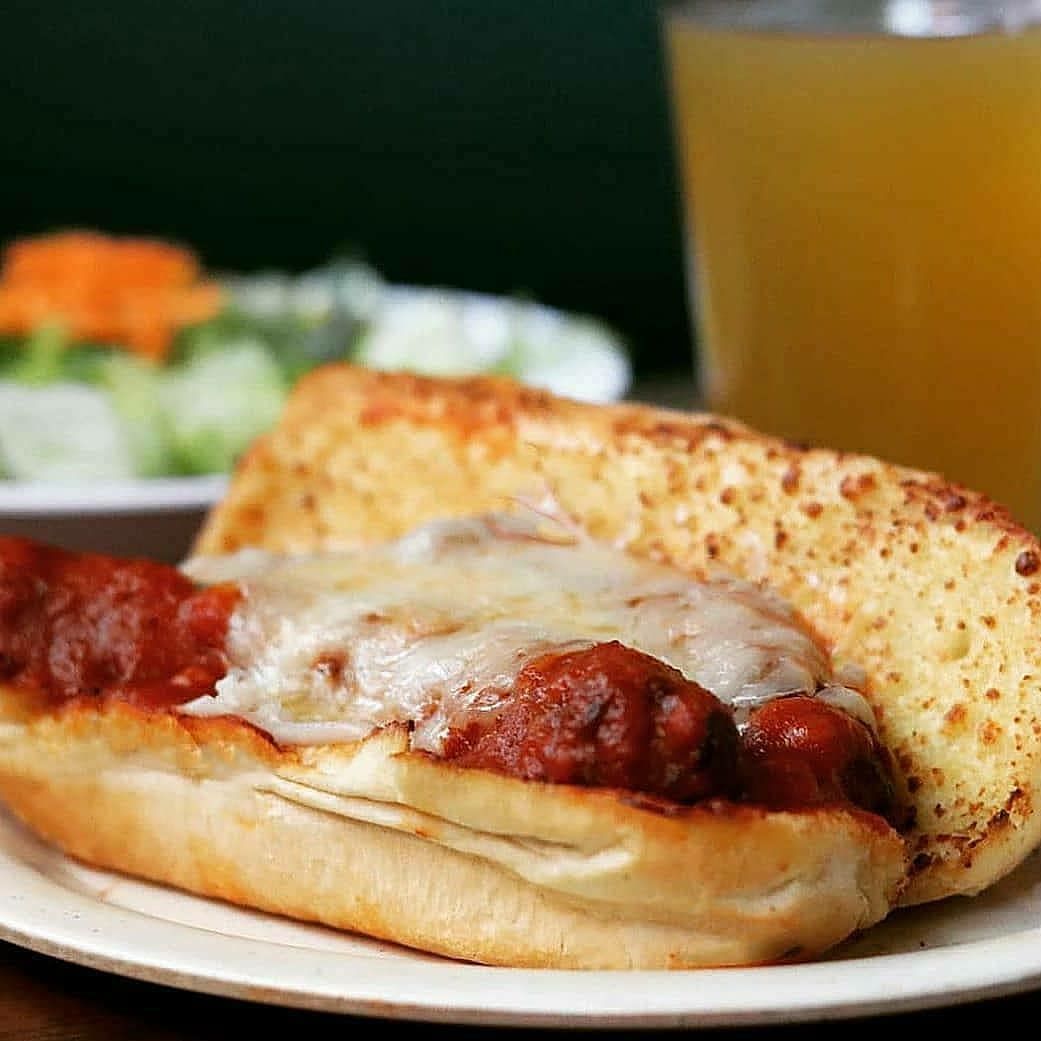 A sub sandwich with meatballs and cheese on a bun on a plate.