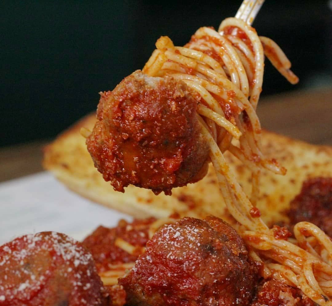 A close up of spaghetti and meatballs on a fork