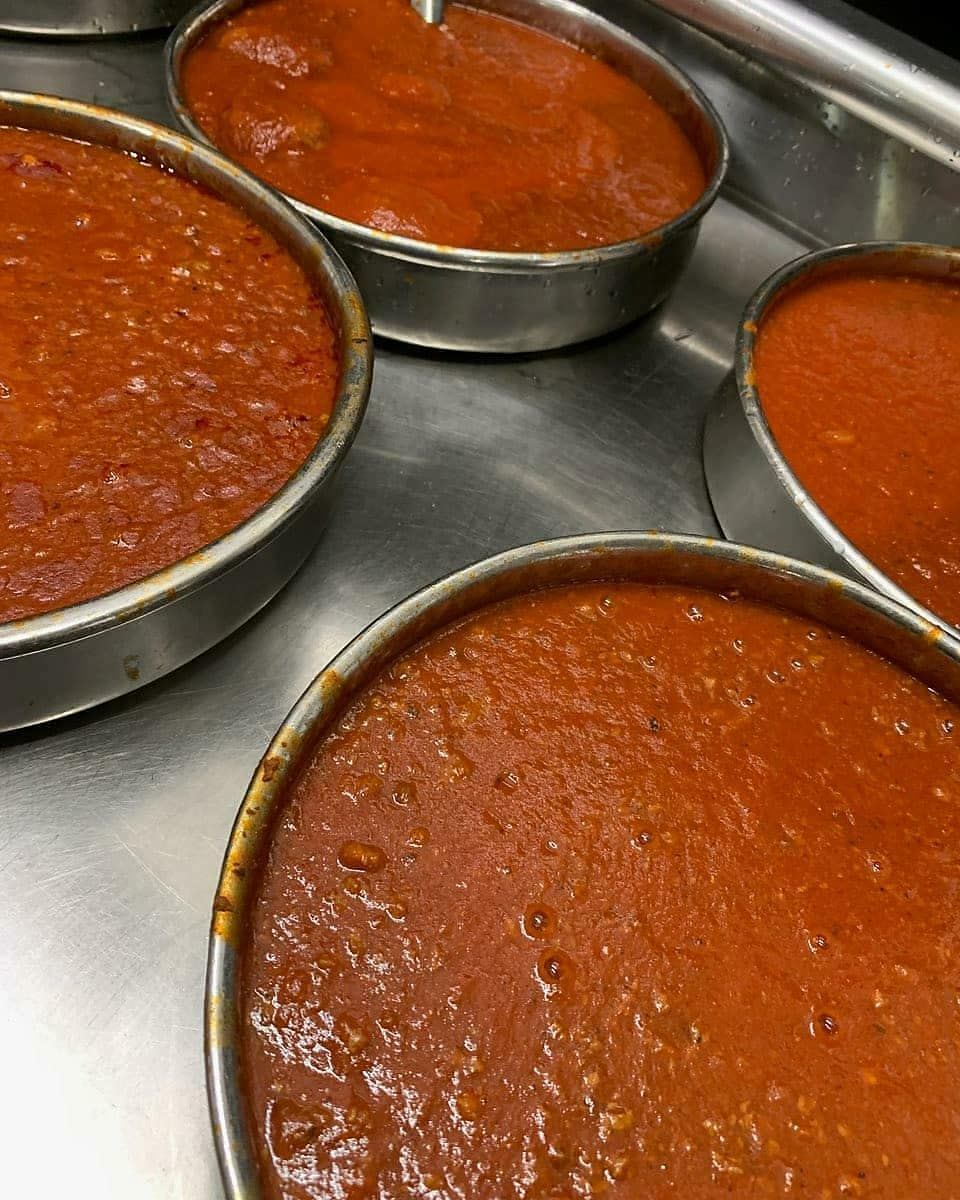 Four bowls of tomato sauce are sitting on a counter