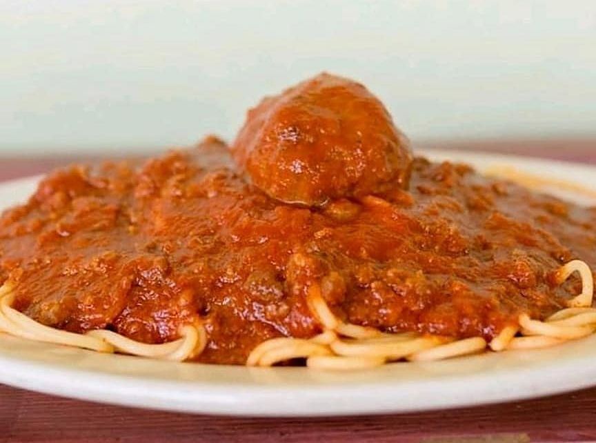 A plate of spaghetti and meatballs with sauce on a table.