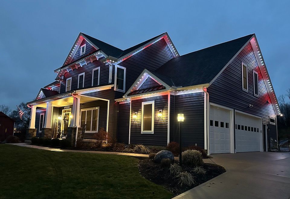 A large house with christmas lights on it is lit up at night.