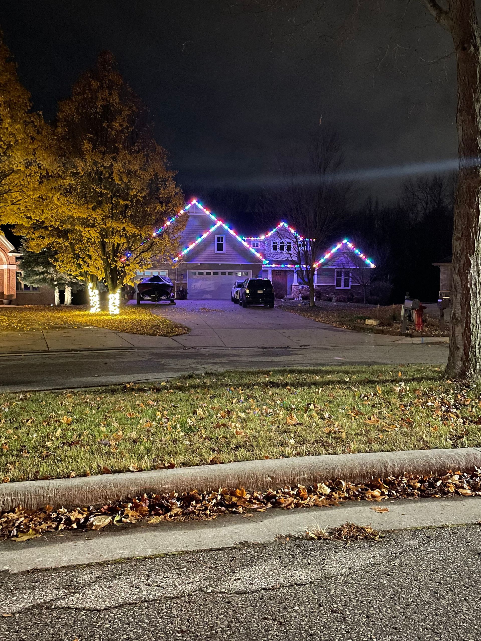 A house with christmas lights on the roof is lit up at night.