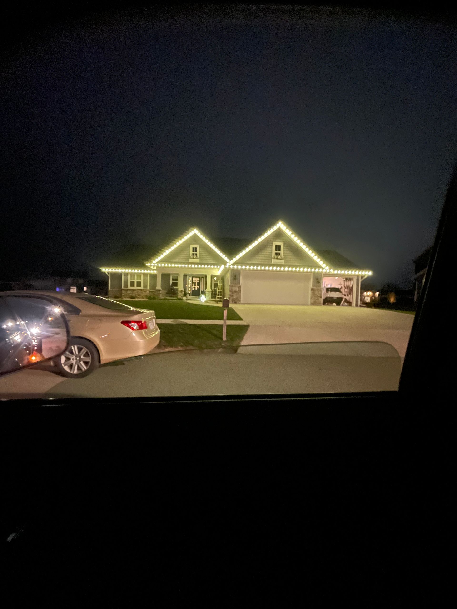 A house with christmas lights on it is lit up at night.