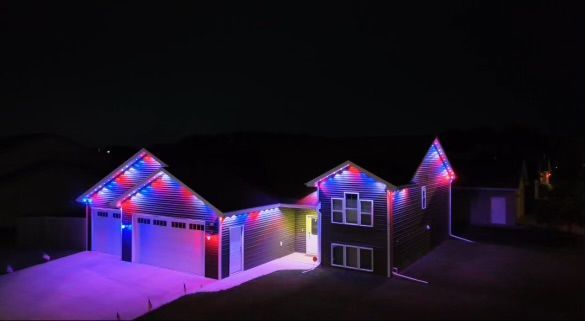 An aerial view of a house decorated with christmas lights at night.