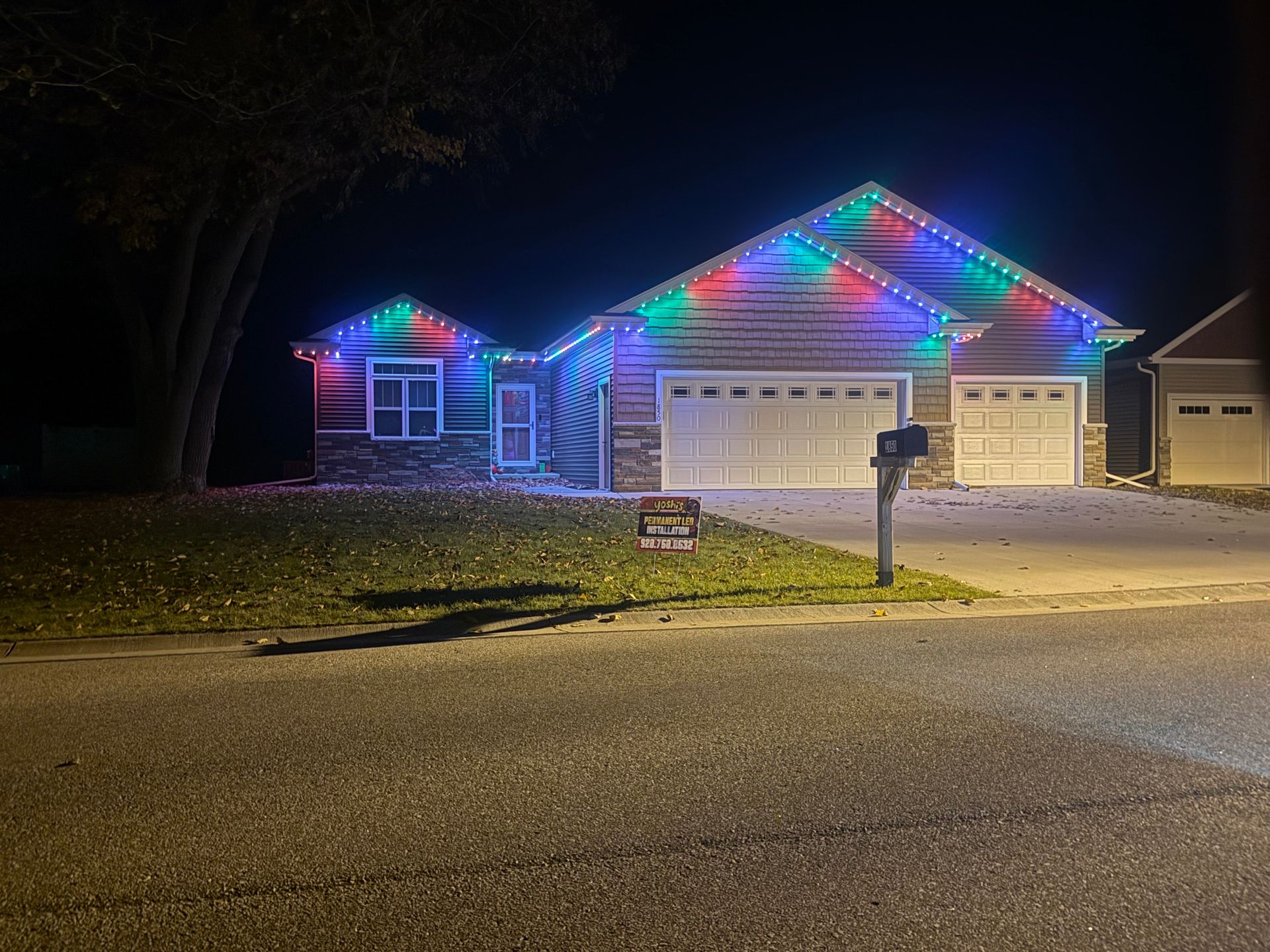 House decorated with white lights for the holidays. Lights outline the roof and trees in front.