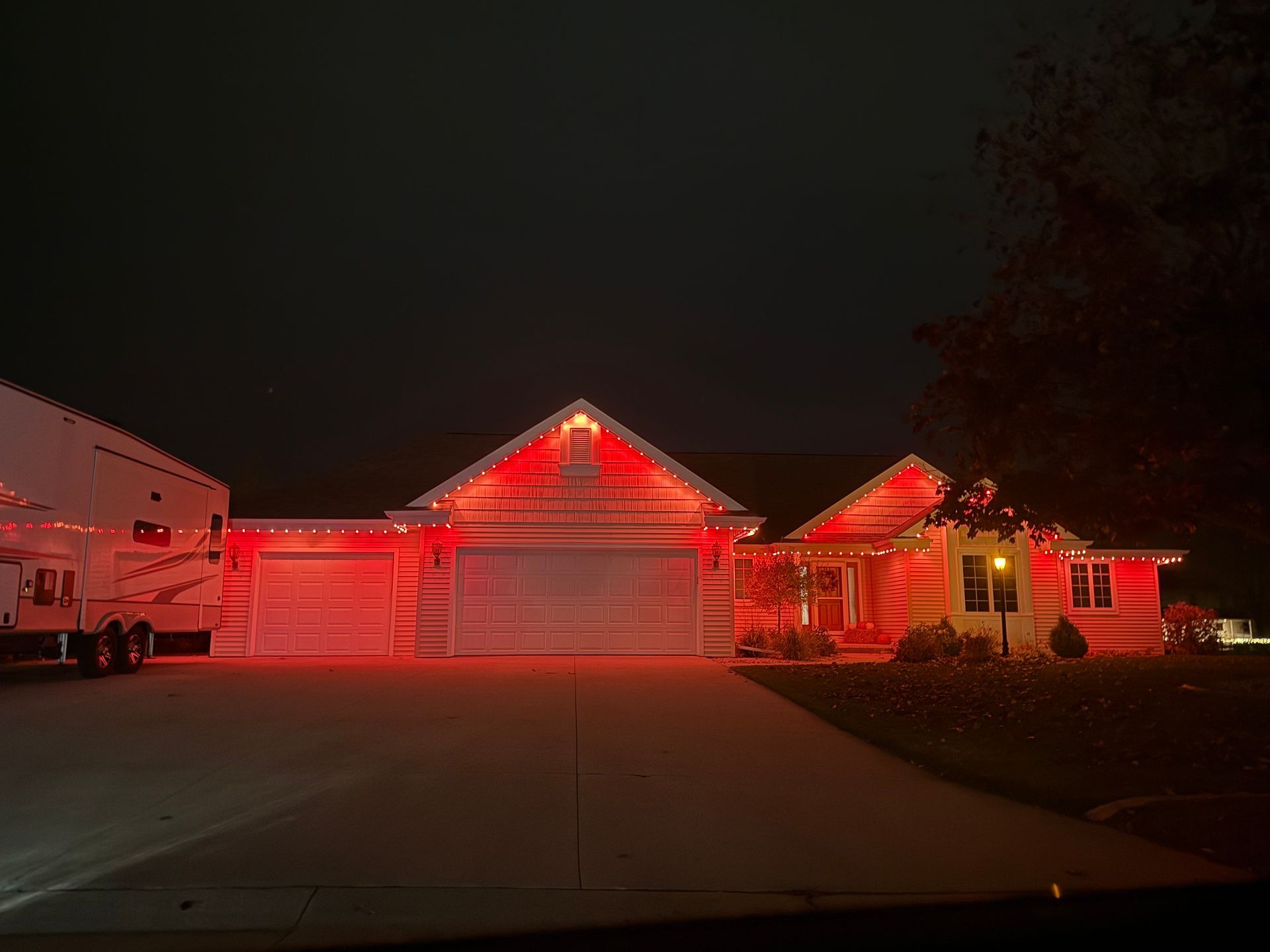 House at night with purple and pink lights lining the roof and above the door.