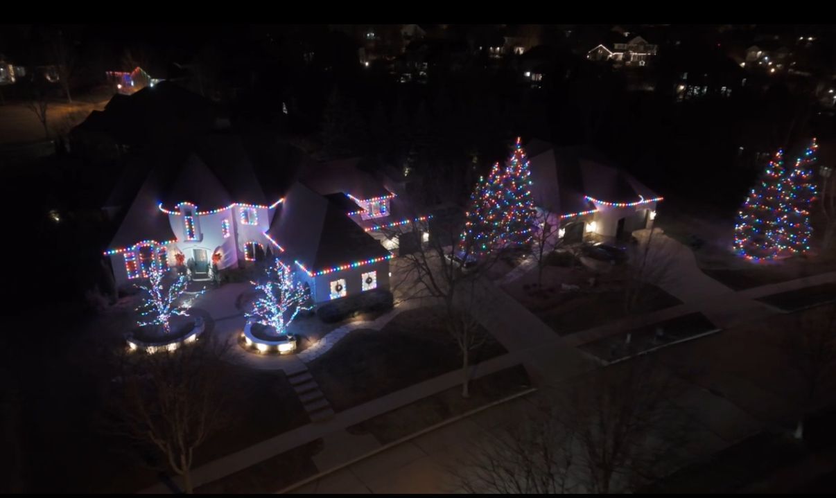 An aerial view of a house decorated with christmas lights at night.