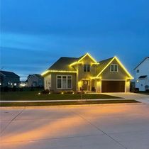 House decorated with yellow Christmas lights against a dusk blue sky.