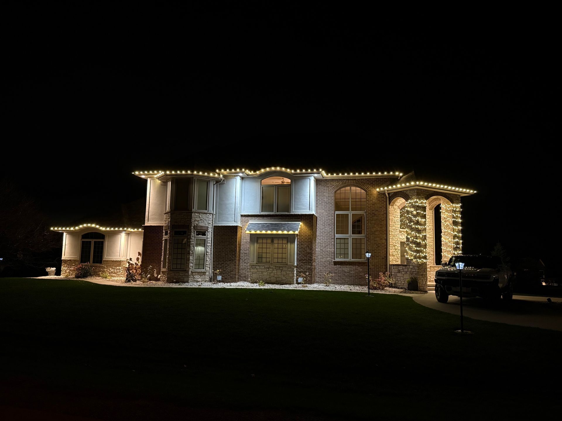 House at night decorated with yellow Christmas lights.