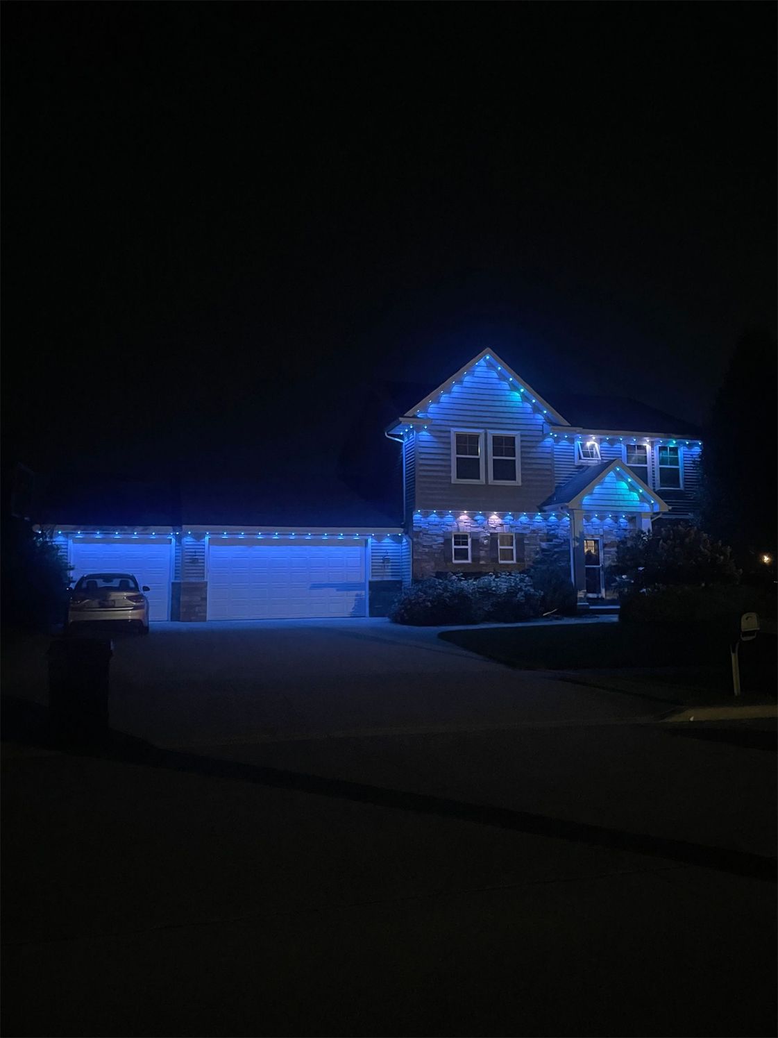 House decorated with blue Christmas lights at night.