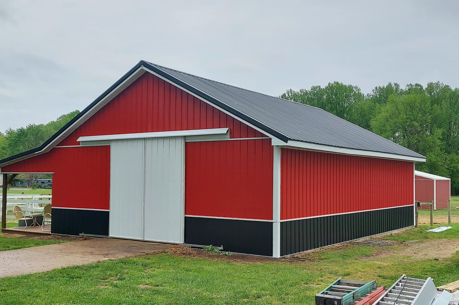 A red barn with a white door is sitting in the middle of a grassy field.