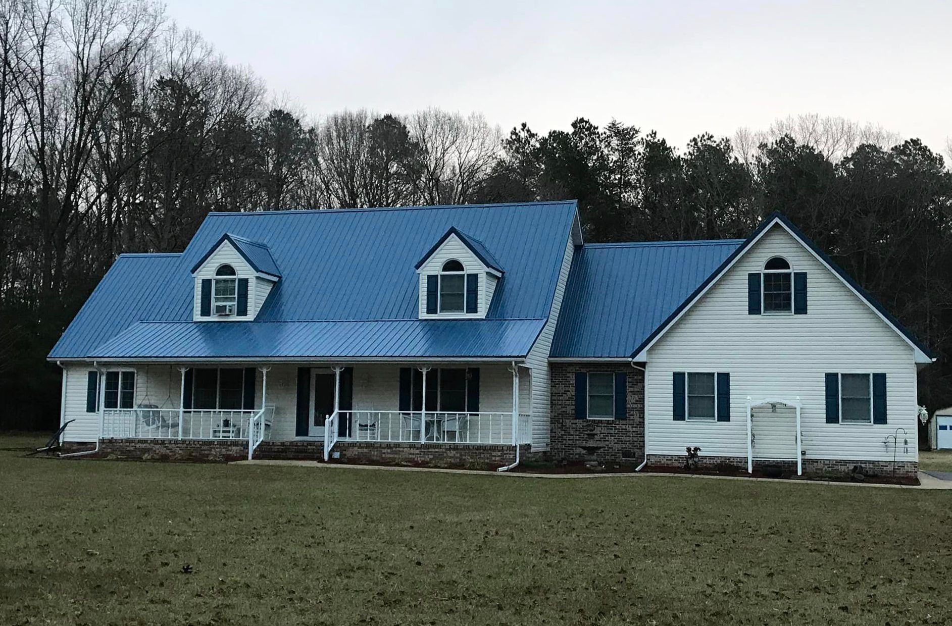 A white house with a blue roof and black shutters.