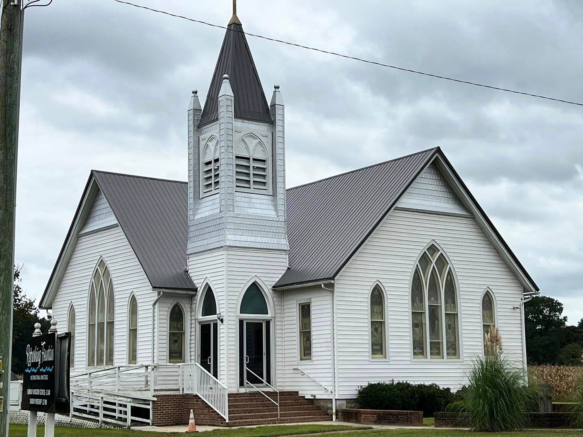 A white church with a gray roof and a steeple.