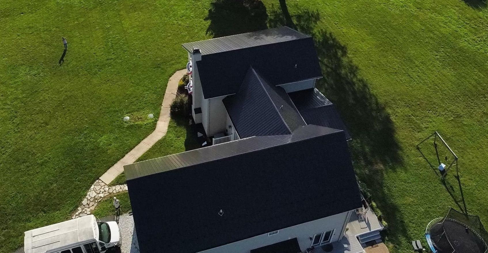 An aerial view of a house with a black roof and a white truck parked in front of it.