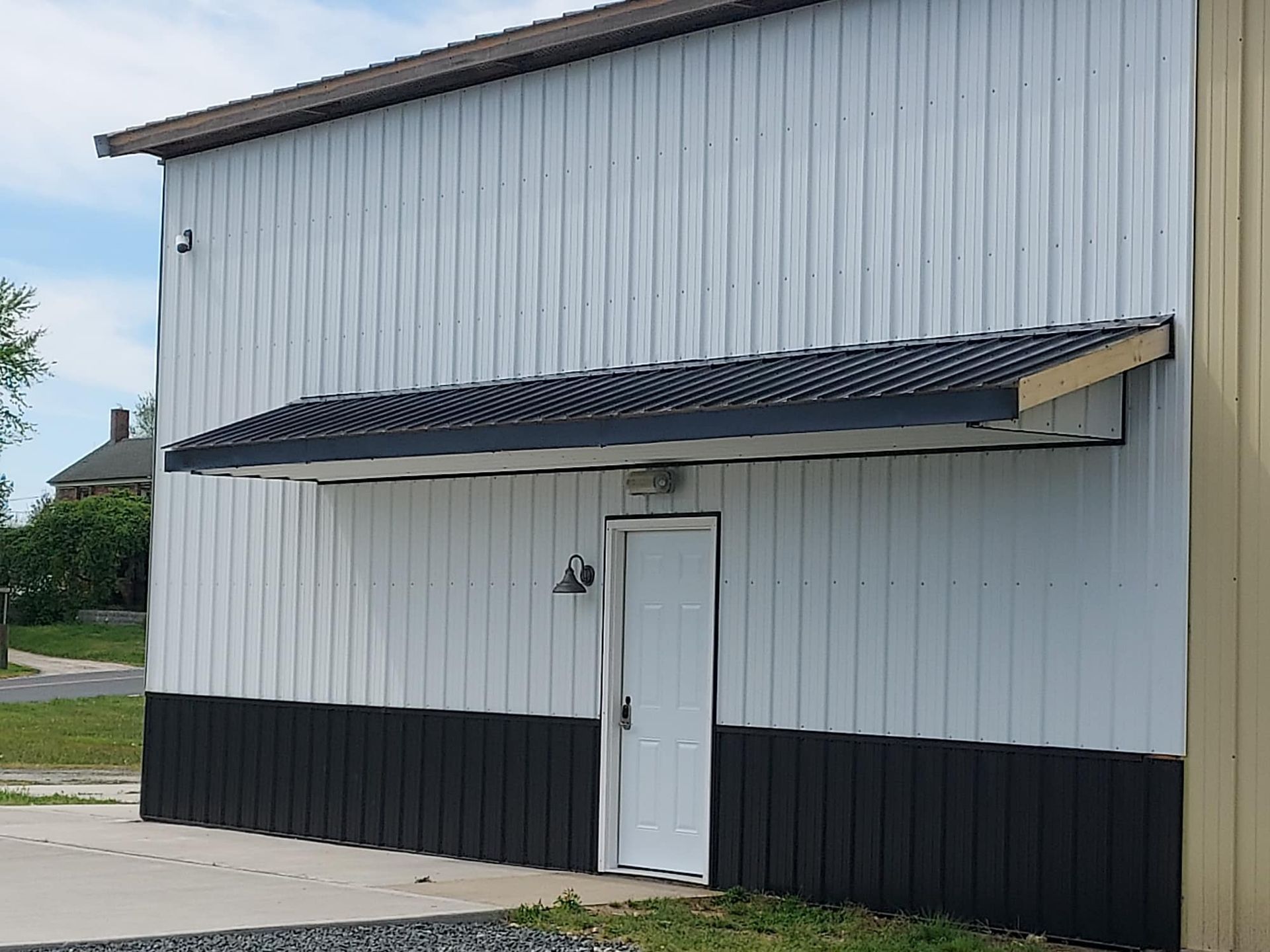 A white building with a black roof and a door.