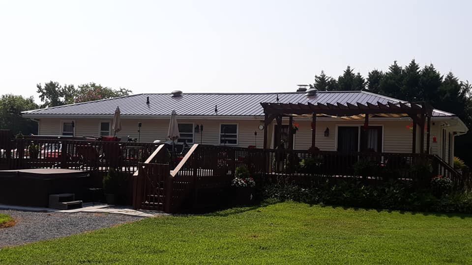 A white house with a metal roof and a large deck
