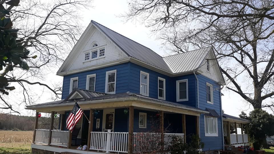 A blue house with a porch and an american flag on it.