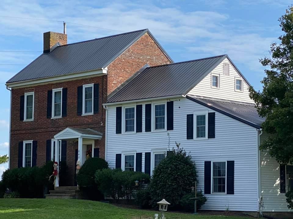 A white house with black shutters sits next to a brick house