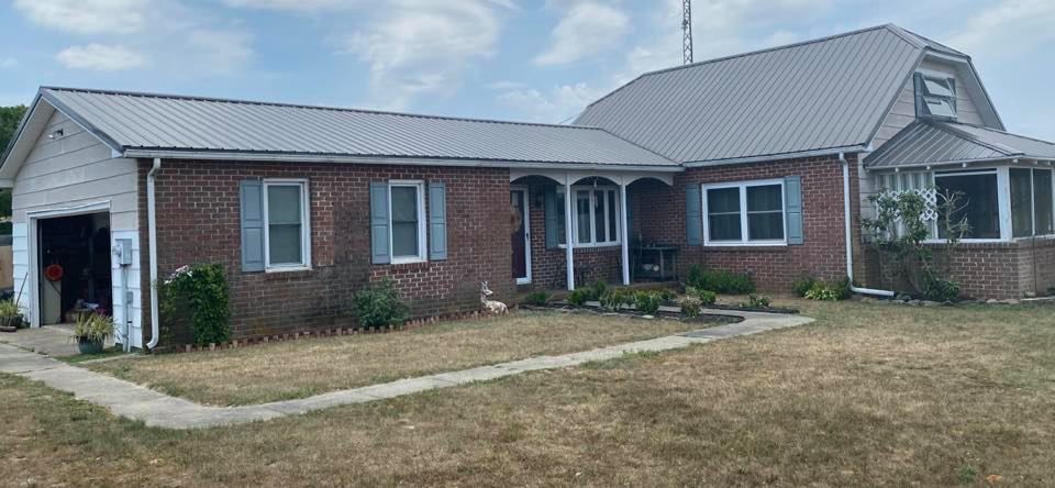 A large brick house with a metal roof and shutters.