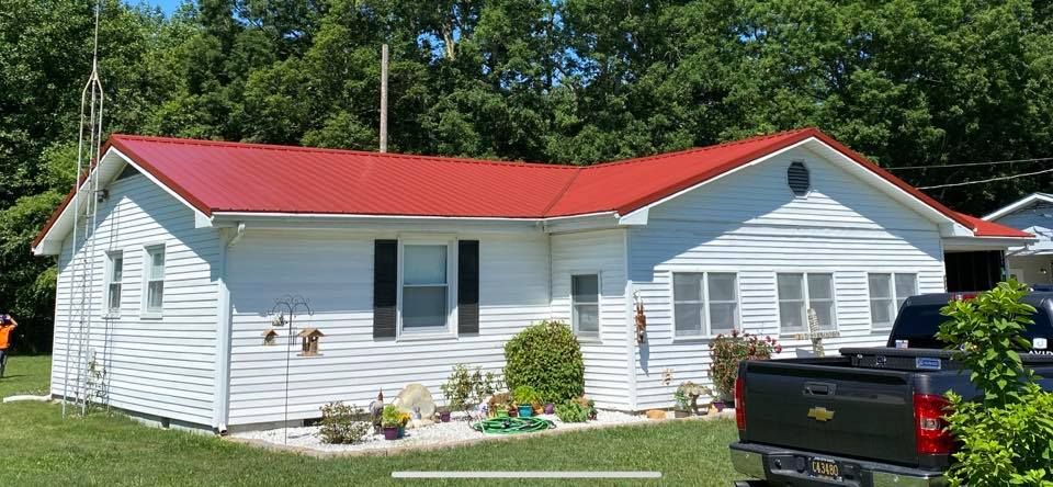 A white house with a red roof and a truck parked in front of it.