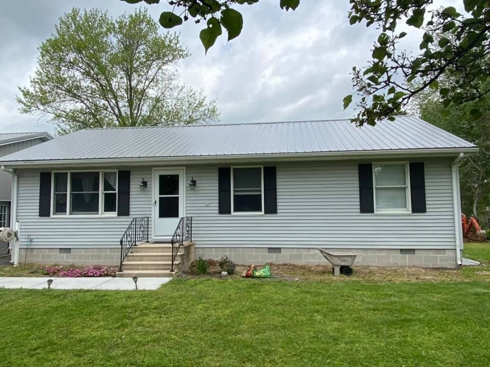 A white house with black shutters and a metal roof