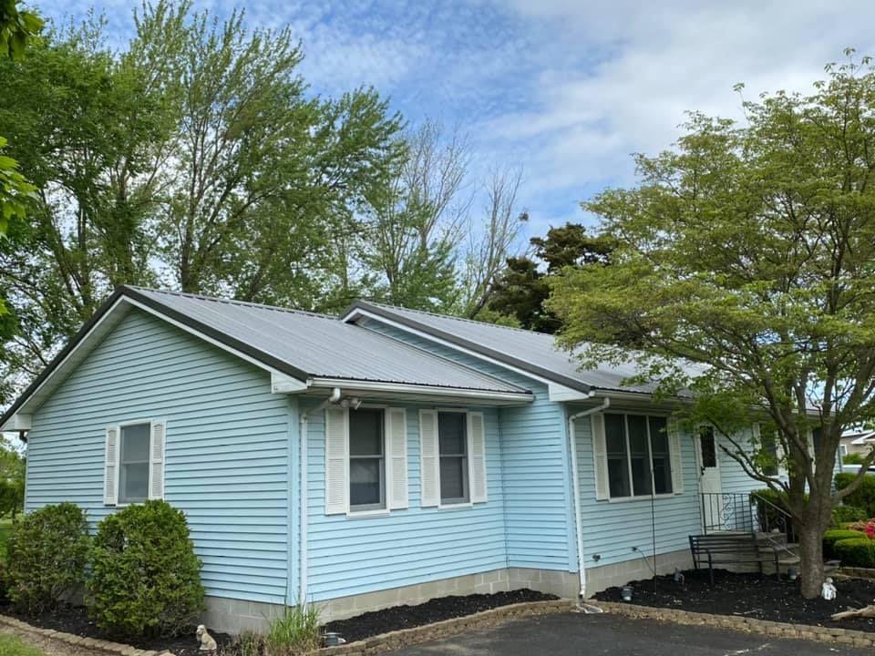 A blue house with a metal roof and white shutters
