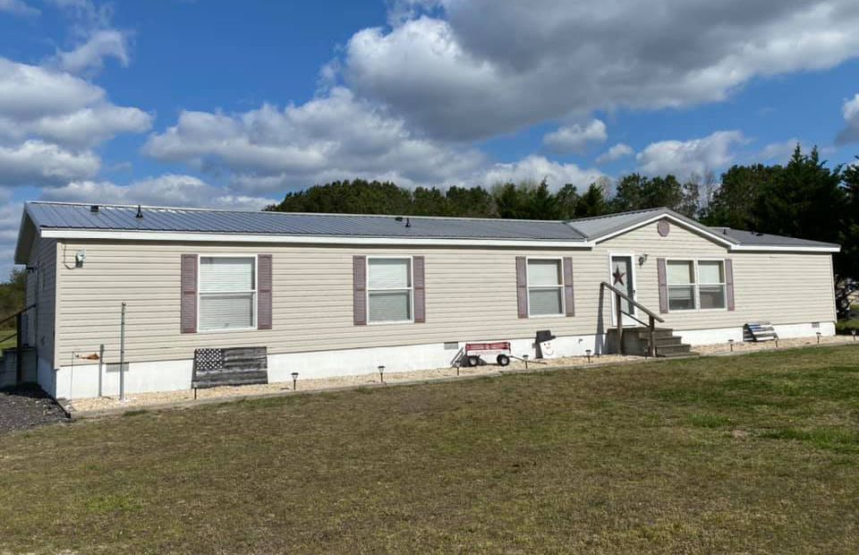 A mobile home is sitting in the middle of a grassy field.