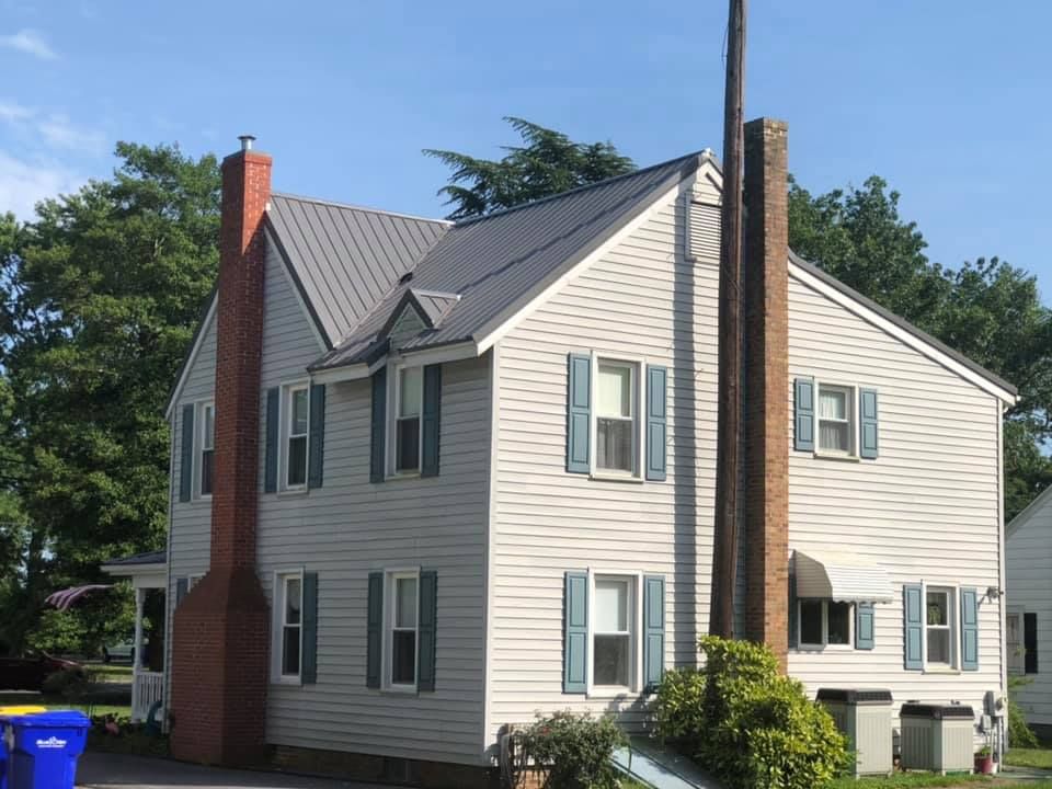 A large white house with blue shutters and a red chimney.