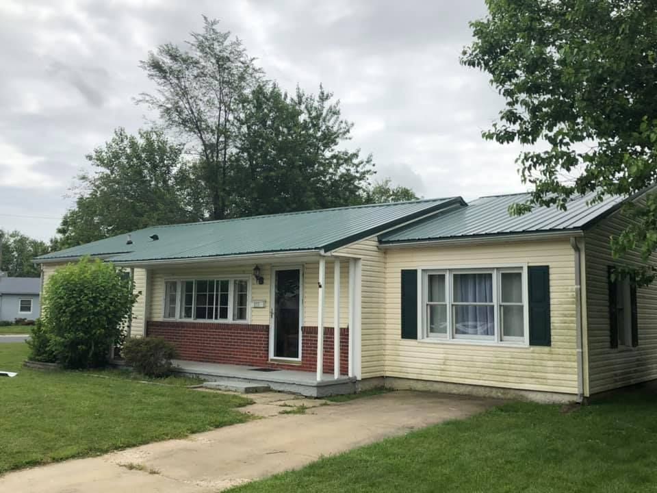 A small house with a green roof and a porch.