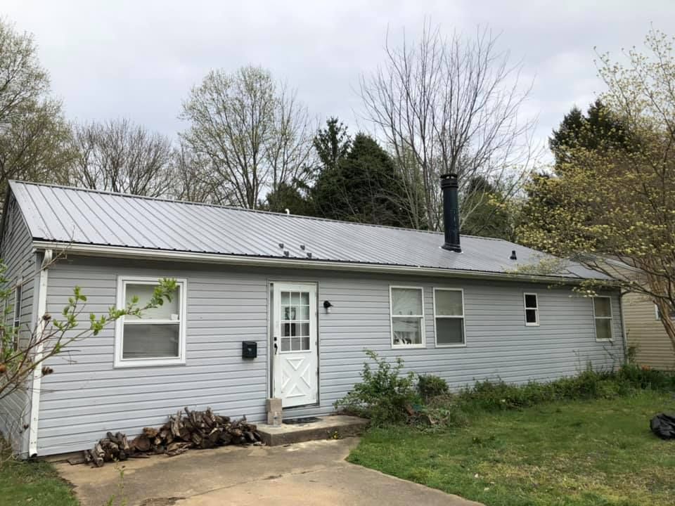 A gray house with a metal roof and a chimney.