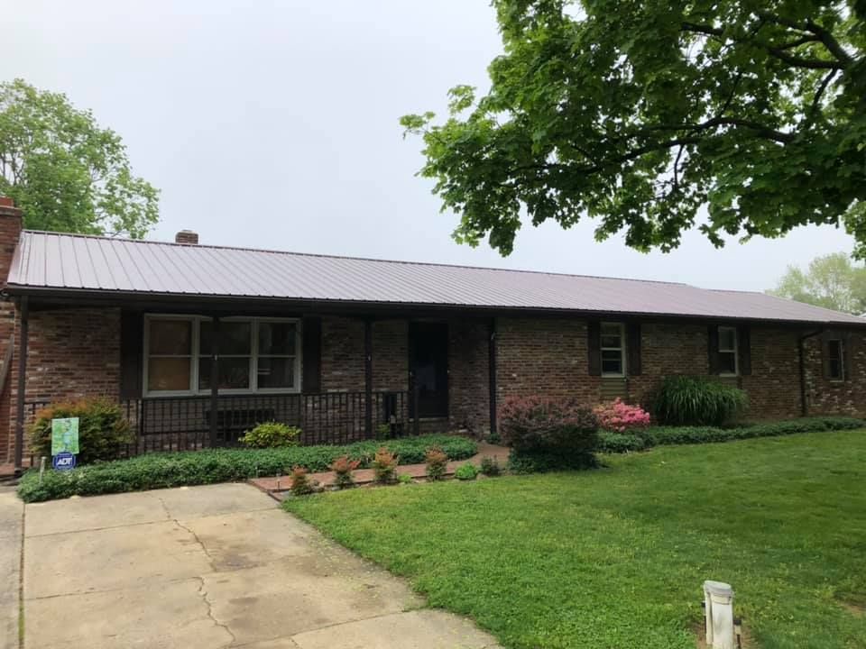 A brick house with a metal roof and a driveway.