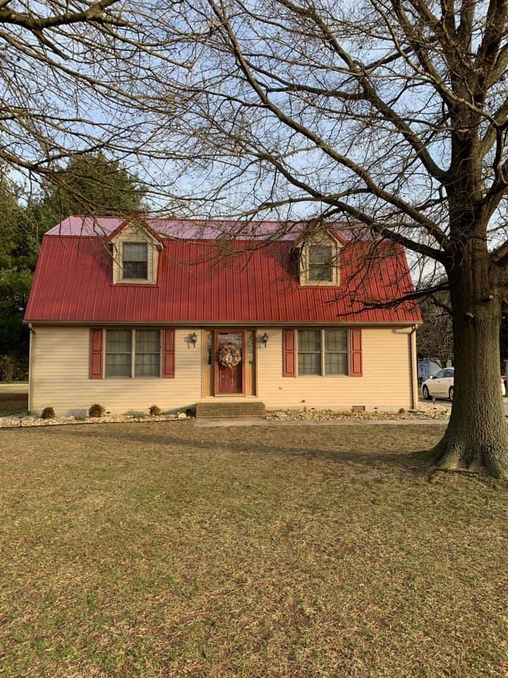 A house with a red roof and a tree in front of it.